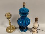 un vase bleu et une bougie dorée posés sur une table blanche