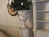 un grand vase rempli de fleurs, posé sur un socle