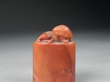 une figurine en jade orange représentant un singe perché sur un rocher