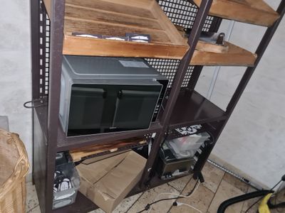 a microwave sitting on top of a shelf in the corner of a room