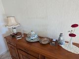 a wooden table with a vase and a lamp on it