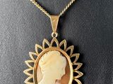 a woman ' s profile is shown in a gold plated pendant