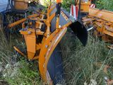 a tractor that is sitting in the grass with a plow behind it