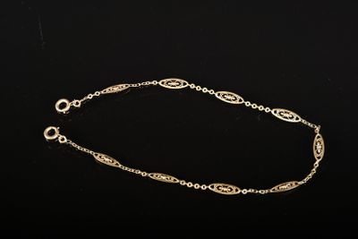 un bracelet en chaîne dorée présentant un motif complexe sur fond noir