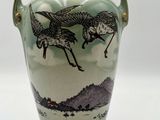 a green vase with a picture of birds on it