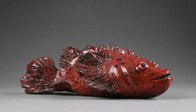 une photo représentant une figurine de poisson rouge posée sur une table