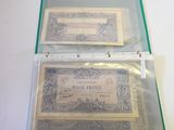 two old bills in a clear case on a table