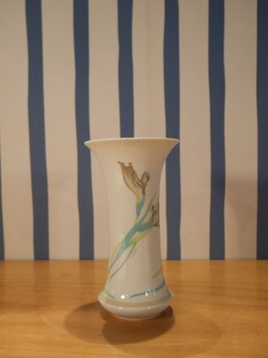un vase blanc posé sur une table en bois à rayures bleues et blanches