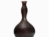 a brown vase that is sitting on a white surface