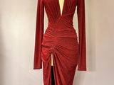 une robe rouge posée sur un mannequin devant un mur rose