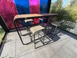 une table et des chaises sur une terrasse, avec un mur coloré en arrière-plan