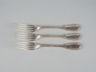 quatre fourchettes accompagnées de couverts, posées sur une surface blanche, sur fond blanc