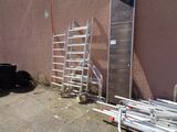 a ladder leaning against a building next to a pile of pipes