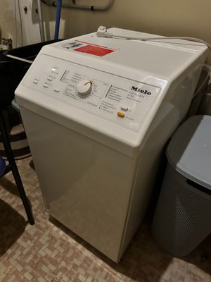 a washing machine and a trash can in a small room