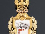 an image of a gold pendant with a picture of a ship on it