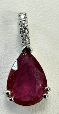 un gros plan d'un pendentif en rubis et diamants sur fond blanc
