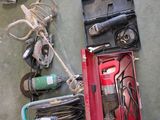 une boîte rouge contenant des outils, posée par terre à côté d'une paire de chaussures