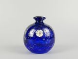 un vase bleu posé sur une table à fond blanc