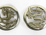 deux boutons métalliques ornés d'un dragon, sur un fond blanc