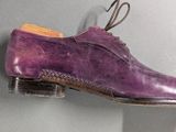 purple shoes hanging on a wall with a shoe hook attached to it