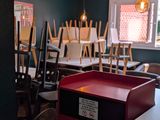 Des tables et des chaises sont alignées dans une pièce où est accrochée une affiche au mur.