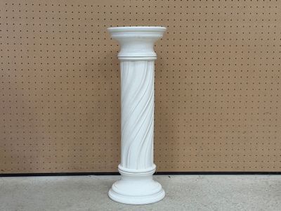 un vase blanc posé par terre devant un mur