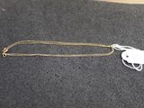 un collier blanc muni d'une étiquette blanche, posé sur une surface noire