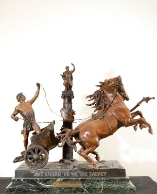 statue en bronze représentant un char tiré par deux chevaux et un homme sur une charrette