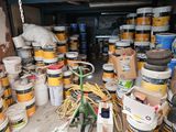 many buckets of paint and other items in a garage