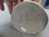 a person that is holding a piece of pottery with writing on it