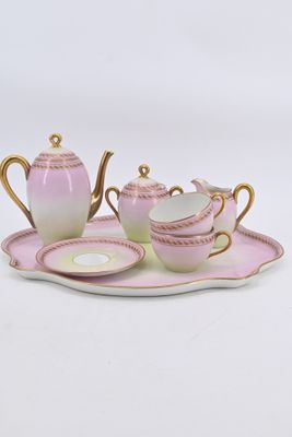a pink and gold tea set on a tray