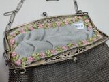 a silver purse with pink flowers on it on a table