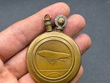 quelqu'un tient une montre de poche en or sur laquelle est représenté un avion