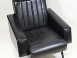 black leather chair with foot rest and foot rest in front of a white background