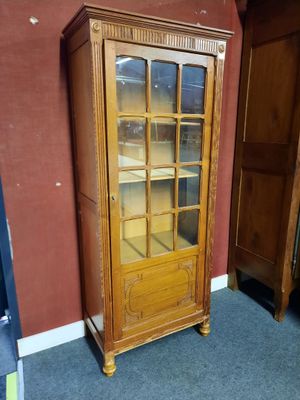 un meuble en bois avec une porte en verre dans une pièce