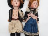 two dolls of a man and a woman are laying on a white surface