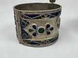 an old silver bracelet with blue and green designs on it