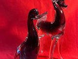 une paire de canards en verre noir et transparent sur fond rouge
