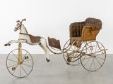 a toy horse pulling a carriage with a horse on it
