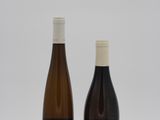 two bottles of wine sitting next to each other on a white surface