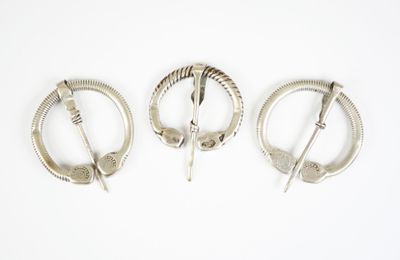trois broches en argent posées sur une surface blanche, sur fond blanc