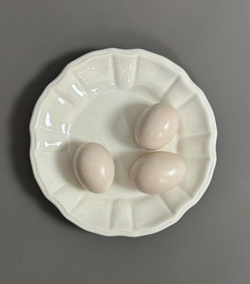 three eggs on a white plate on a gray table