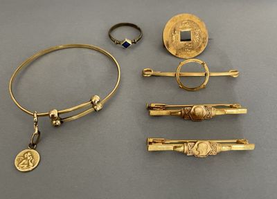 several gold jewelry items are displayed on a gray surface