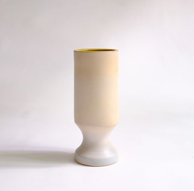 un vase blanc bordé de jaune, posé sur une surface blanche