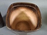 a brown bowl sitting on top of a table next to a cell phone