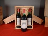 three bottles of wine in a wooden box on a table