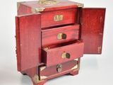 a small red chest of drawers with gold handles