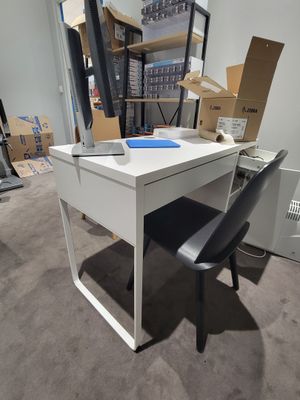 un bureau blanc avec une chaise noire dans une pièce