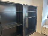 une bibliothèque noire dans un coin de la pièce, près d'une fenêtre
