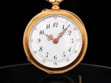 une image représentant une montre de poche en or posée sur une surface noire